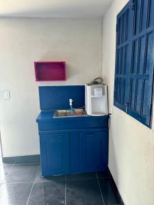 a bathroom with a blue sink and a microwave at Casa Tô na Onda in Prado