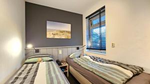 a bedroom with two beds and a window at Waddenresidentie Ameland - 2 en 4 persoons appartementen in Buren