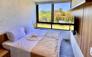 a bed in a room with a large window at Casa 09 - Villa Cotinguiba in Tatuamunha +48 photos