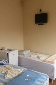2 Betten in einem Zimmer mit einem TV an der Wand in der Unterkunft Hospedaria Coração de Pedra in São Thomé das Letras