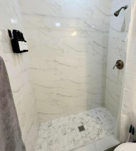 a bathroom with a shower with white marble tiles at Private studio by Miami International Airport in Miami +17 photos
