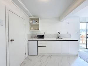 a white kitchen with a sink and a microwave at Unit 5, Fenton Summer Lodge in Rotorua