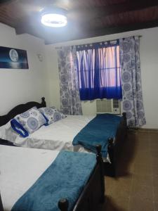 two twin beds in a bedroom with blue curtains at Punto Descanso in Corrientes