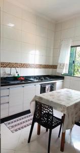 a white kitchen with a table and a stove at Quarto Privativo Santa Rita do Sapucaí in Santa Rita do Sapucaí