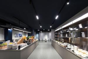 un ristorante con un lungo bancone con piatti e piatti di Atour Light Hotel Xiamen Convention and Exhibition Center Software Park Phase II a Xiamen
