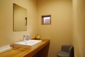 a bathroom with a sink and a mirror and a chair at 貸切温泉旅館ー倉持ー湯畑まで徒歩1分 in Kusatsu