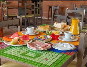 a table with plates of food and cups on it at Pousada Beija-Flor in Icapuí