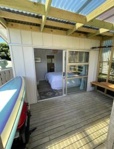 a room with a bed on a deck at Studio at Otama Beach in Opito Bay +20 photos