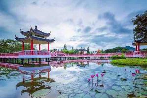 un étang dans un parc avec des bâtiments roses et des fleurs dans l'établissement Al-Waris Beseri Poolstay Spacious 6 Bedrooms, à Alor Tampang