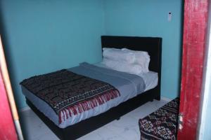 a blue room with a bed with white sheets and pillows at Novena Bungalow in Pulau Helihana +10 photos