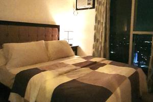 a bedroom with a large bed with a window at Modern and Cozy 2-Bedroom Condo in Prime Location in Manila +10 photos