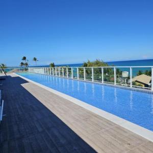 a large swimming pool with the ocean in the background at Nixxus Luxo e requinte á 50 m do mar e próximo as piscinas Naturais in Porto De Galinhas