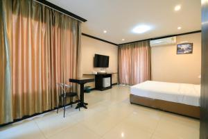 呵叻Triton Hotel Nakhonratchasima โรงแรมไททัน的一间卧室，配有一张床、一张书桌和一台电视