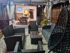 un patio con sedie, tavoli e un ombrellone di Villa Kasanaco avec vue sur la mer a Case-Pilote
