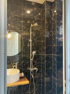 ein schwarz gefliestes Bad mit einem Waschbecken und einer Dusche in der Unterkunft Hoang Gia Hotel in Da Lat