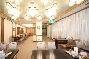 a dining room with tables and chairs and chandeliers at Hotel Il Viale Hachinohe in Hachinohe