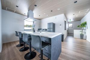 eine Küche mit einer Bar mit Stühlen und einem Waschbecken in der Unterkunft THE Sakura in Kami-furano
