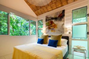 a bedroom with a bed with blue pillows and windows at Bungalow in Santa Teresa Beach +26 photos