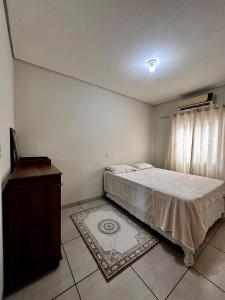 a bedroom with a bed and a window and a rug at Casa confortável em condomínio in Ponta Porã