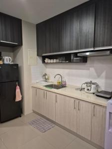 a kitchen with wooden cabinets and a black refrigerator at Lorena 's House in Tiwi