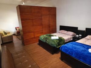 a bedroom with two beds and a large wooden door at Suite M a p l e - El Renacimiento Suites in Cuenca