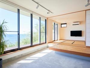a living room with large windows and a flat screen tv at 木の匙Kino-saji in Ibusuki