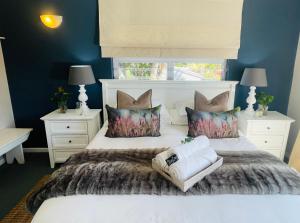 ein Schlafzimmer mit einem weißen Bett und zwei Nachttischen in der Unterkunft Cape Cottages in Bergvliet + 27 Fotos