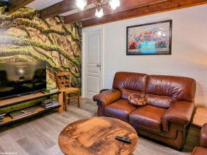a living room with a leather couch and a tv at Grande Maison Familiale Rénovée à Froideterre - FR-1-583-374 in Froideterre