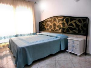 a bedroom with a large bed and a night stand at Affittacamere Da Angela in Villasimius