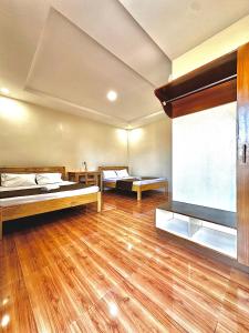 a large room with two beds and a wooden floor at Selline Bed and Breakfast in Bacnotan