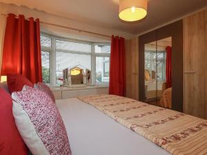a bedroom with a bed with red curtains and a mirror at Garden View in Newquay