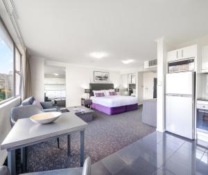 a hotel room with a bed and a living room at Oaks Sydney Hyde Park Suites in Sydney