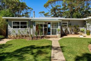 a house with a green lawn in front of it at Kirby's Berrara Beach House in Berrara