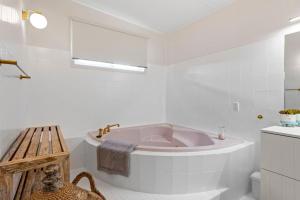 a white bathroom with a tub and a sink at Kirby's Berrara Beach House in Berrara +28 photos