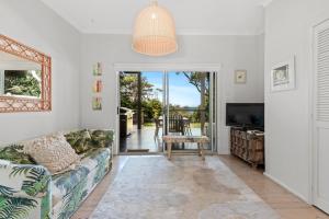 a living room with a couch and a tv at Kirby's Berrara Beach House in Berrara