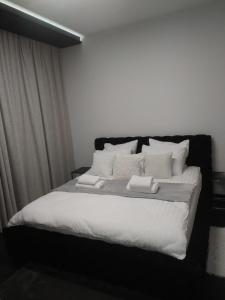 ein Schlafzimmer mit einem Bett mit weißen Laken und Kissen in der Unterkunft Baltic Riviera Apartments -Solmarina in Wiślinka
