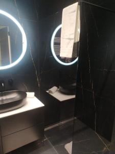 ein schwarzes Badezimmer mit Waschbecken und Spiegel in der Unterkunft Baltic Riviera Apartments -Solmarina in Wiślinka