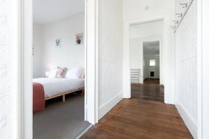 Dormitorio blanco con cama y pasillo en Charming Inner City Stay with parking & wifi, en Launceston