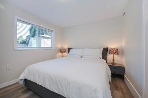 a white bedroom with a large bed and a window at Cozy Home with 3BR 4Bath near Richmond Steveston Village in Richmond