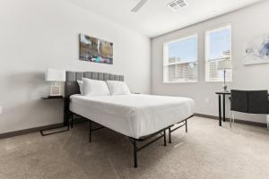 a white bedroom with a large bed and two windows at Cozysuites PHX RORO Gym Pool Pets Parking #17 in Phoenix
