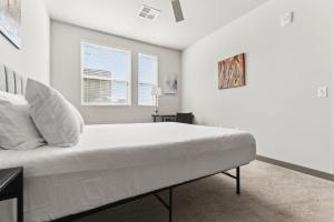a white bedroom with a bed and a window at Cozysuites PHX RORO Gym Pool Pets Parking #17 in Phoenix