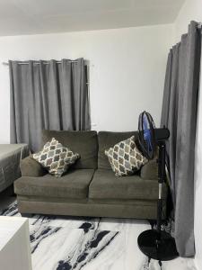 a living room with a green couch with pillows at White Room Sparks in Spanish Town