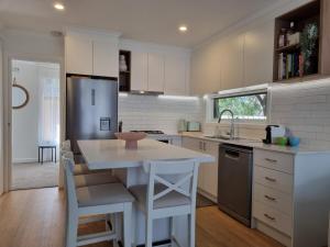 a kitchen with a table and a sink and a refrigerator at Boardwalk by the Bay in Rosebud