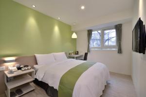 Un dormitorio con una cama grande y una ventana en Green Hotel - Fengjia, en Taichung