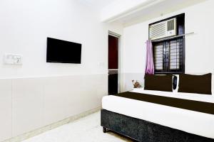 德里Super Hotel O Fazalpur的一间卧室，墙上有一张床和一台电视