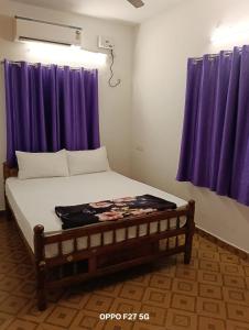 a bed in a room with purple curtains at Vj Villa Home Stay in Puducherry