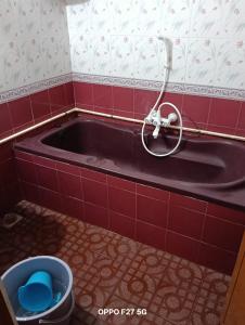 a bath tub in a red tiled bathroom with a bucket at Vj Villa Home Stay in Puducherry
