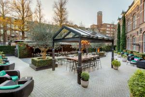 a patio with tables and chairs in a garden at The College Hotel Amsterdam, Autograph Collection in Amsterdam