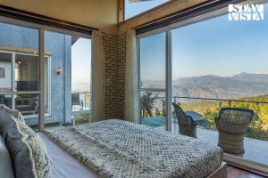 a bedroom with a bed and a large window at StayVista at Pleasance Villa with BBQ & Bonfire in Rānīkhet