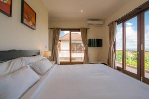 une chambre avec un lit blanc et une grande fenêtre dans l'établissement Green GWK Villa, à Jimbaran